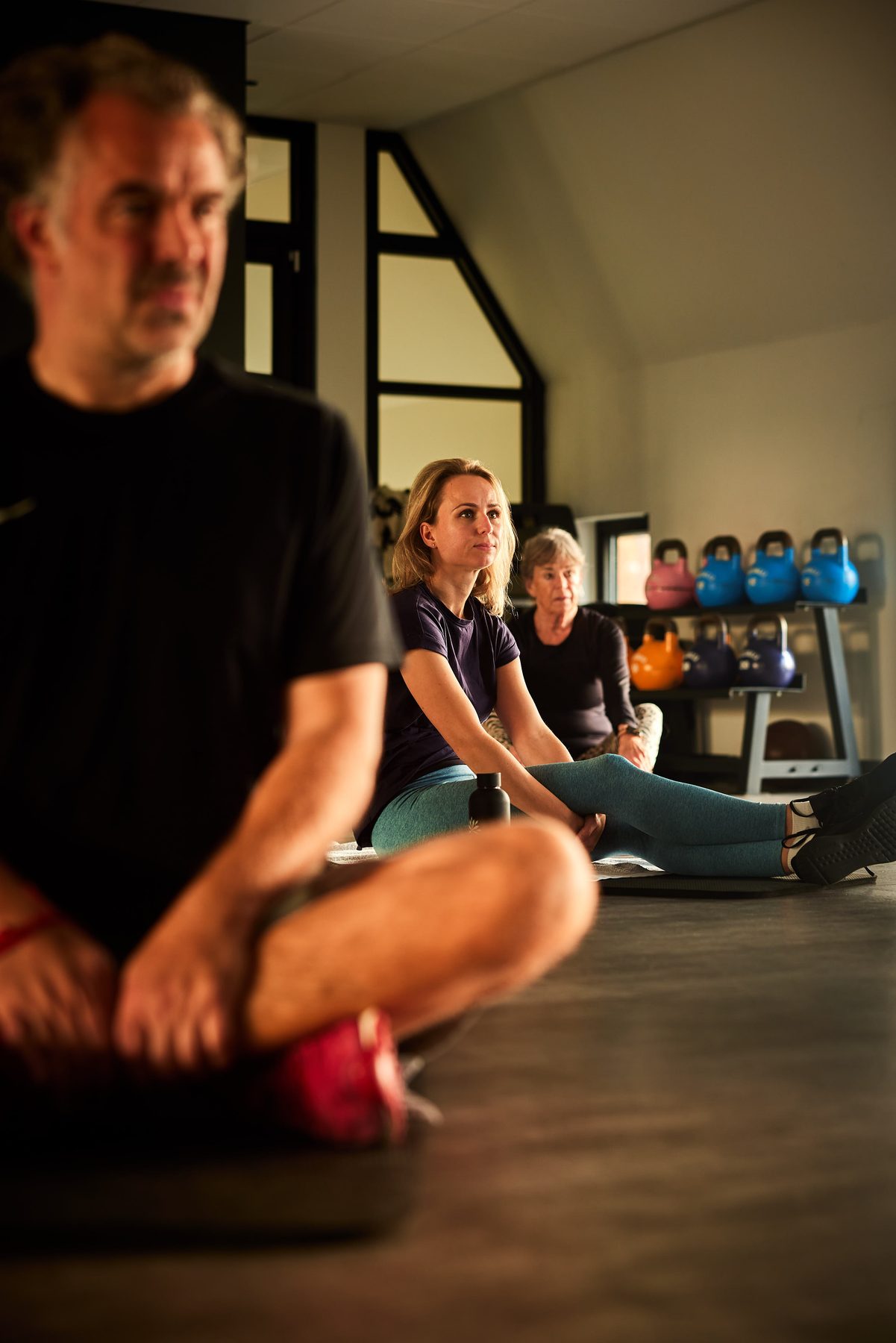 Groep sporters op de vloer tijdens uitleg in de HIIT-zaal