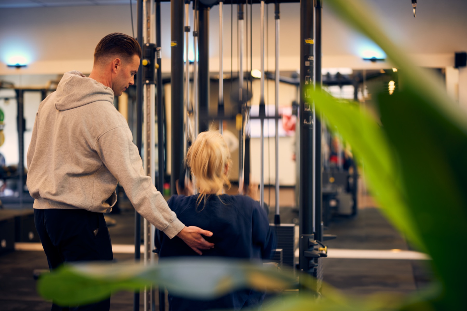 Personal trainer guiding a client at the cable station
